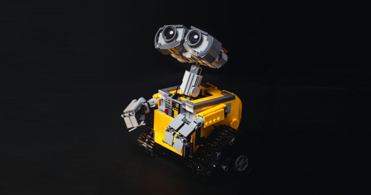 Photo: Isolated black background with a Lego style yellow and grey Robot.